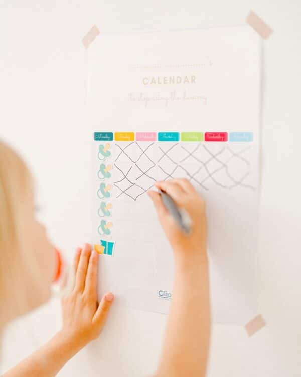 Enfant trace des croix sur un calendrier tape sur le mur.